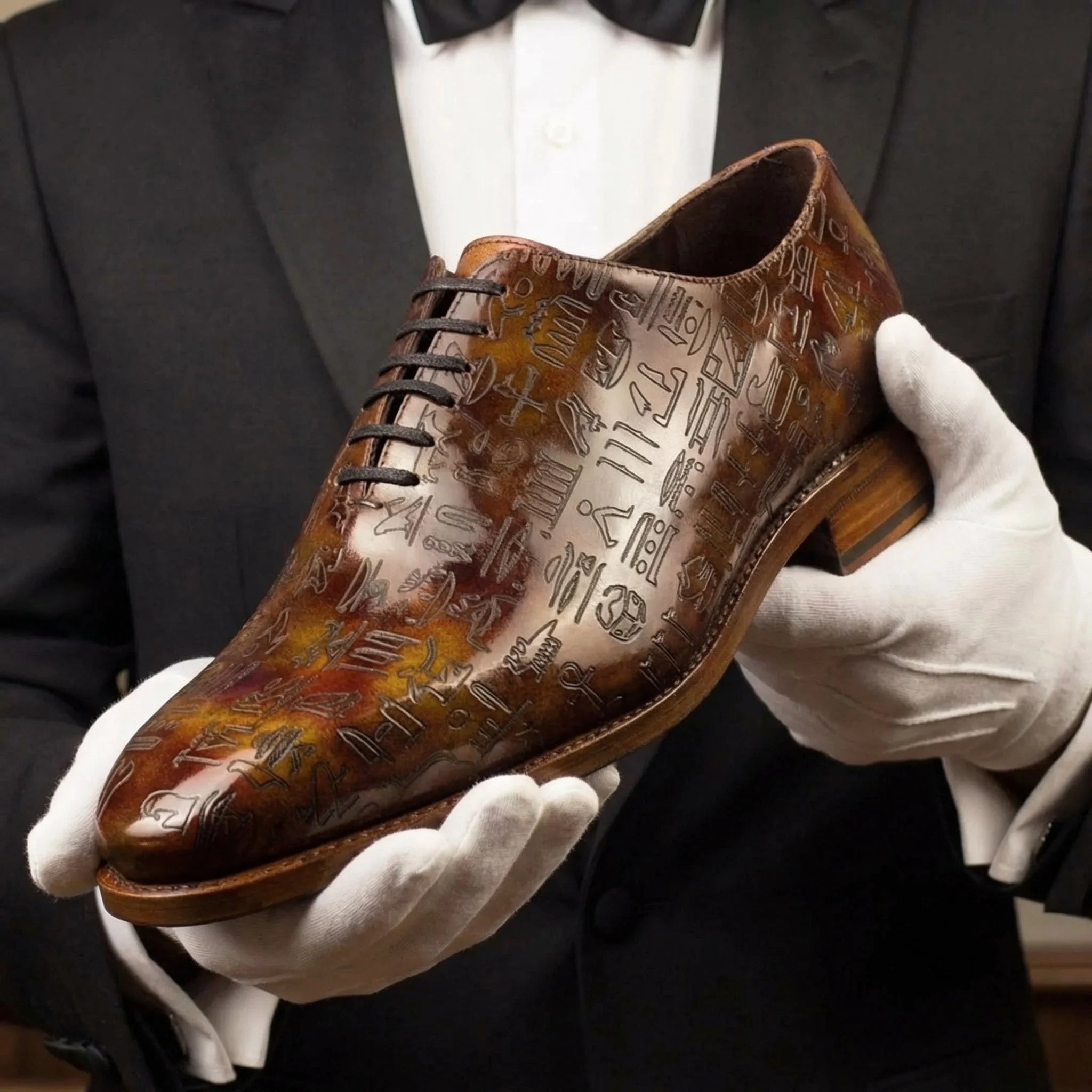 A polished brown leather oxford chisel toe featuring intricate hieroglyphic engravings in egyptian patina wholecut